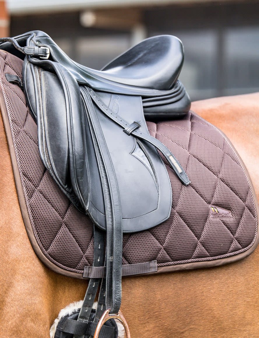 A brown Back on Track Airflow dressage saddle pad under a black dressage saddle