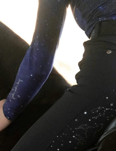 A rider in navy Dapplebay full seat breeches with a sparkle grip pattern beside her horse