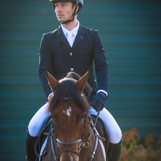 A rider in a navy Alessandro Albanese show coat on a bay horse