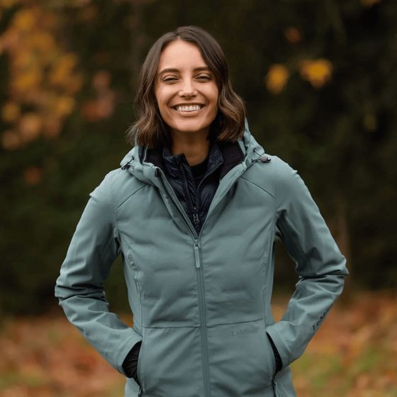 A smiling rider in a LeMieux sage green softshell jacket