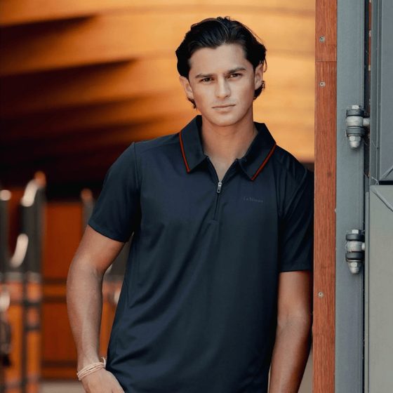 A rider in a navy LeMieux men's polo shirt by the stable door