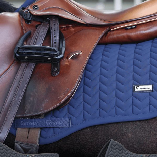 A navy Shires ARMA quilted saddle pad under a brown leather saddle