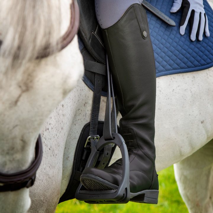 Rider’s leg in a black Shires Moretta Gianna leather field boot in the stirrup on a gray horse