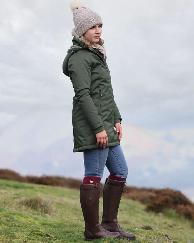 A woman in a green coat and brown Shires Moretta country boots on a hillside